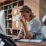woman feeling eye pain while overworking on desktop computer.
